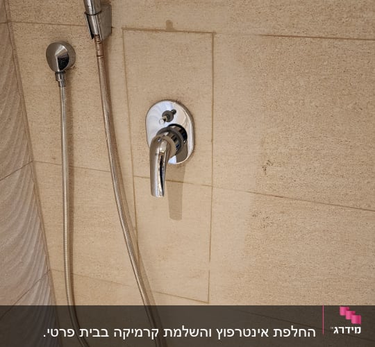 ראש מקלחת וברז על קיר אריחים